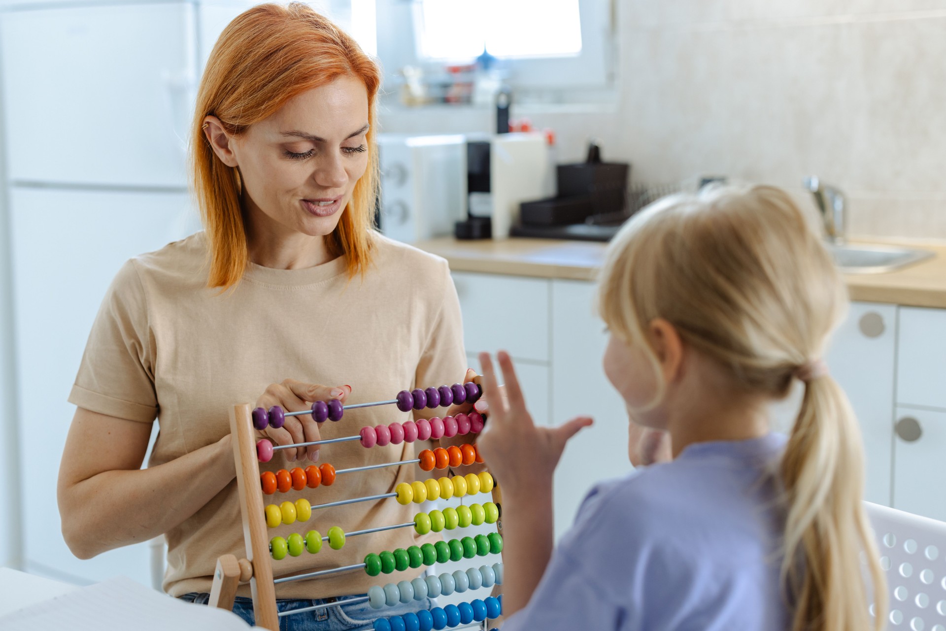 Mother teaching daughter with colorful abacus in kitchen setting